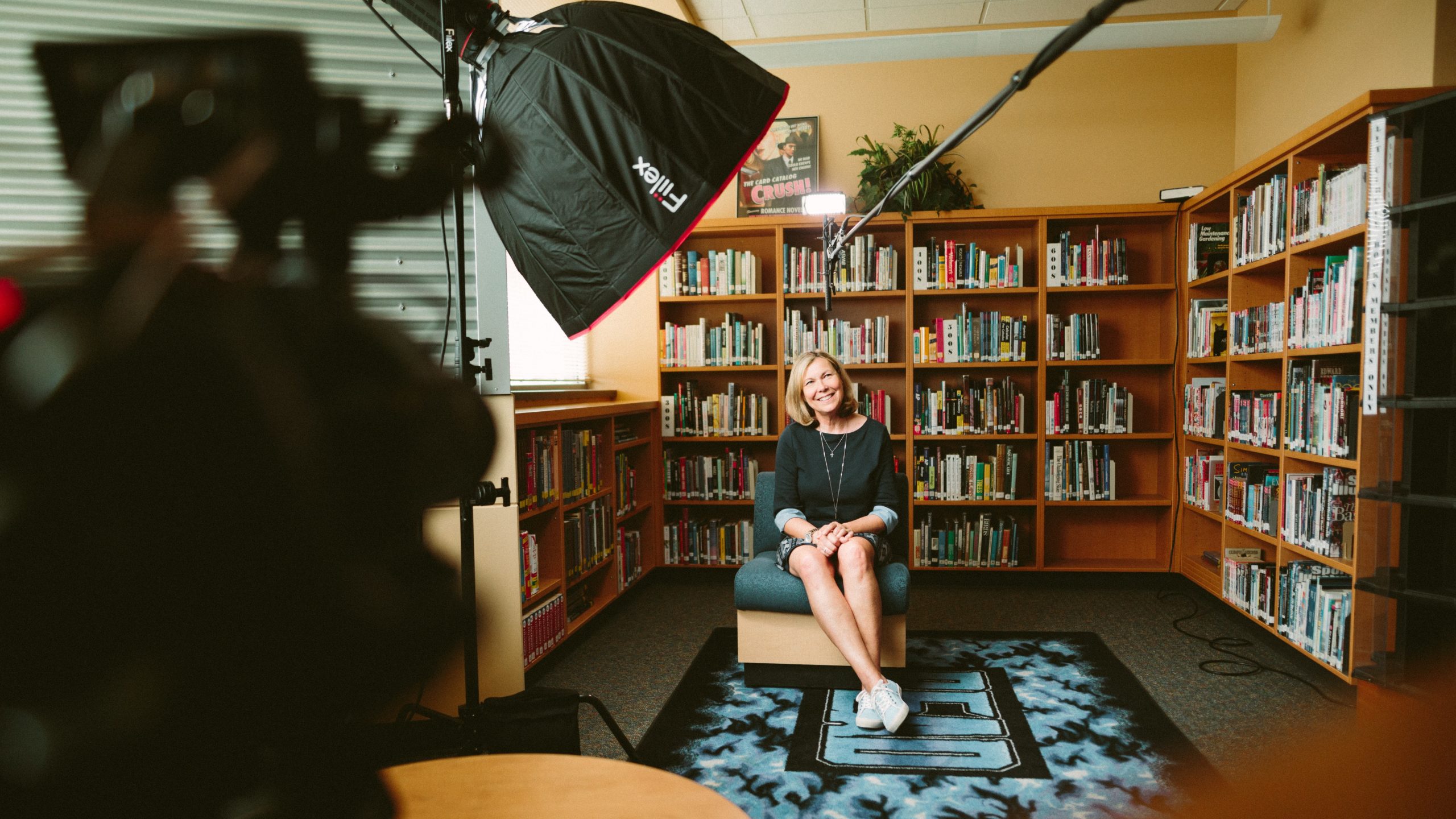 femme qui tourne une vidéo assise dans une bibliothèque